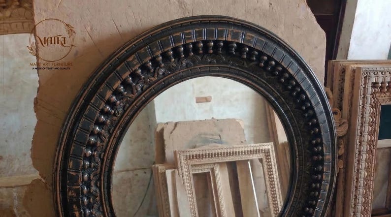 Pu&ograve; includere: Uno specchio ovale con cornice marrone scuro e dettagli ornati. La cornice presenta un design intagliato e strutturato. Lo specchio &egrave; esposto con altre cornici in legno, suggerendo un tema di arredamento o decorazione per la casa.