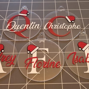 Gepersonaliseerde acryl kerstballen met naam, initialen, kerstmuts en kerstboomversieringen.