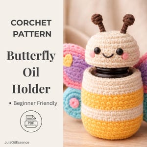 Pode incluir: Um porta-óleo de borboleta de crochê com cabeça creme, corpo listrado amarelo e creme e antenas marrons. O suporte tem um rosto sorridente e bochechas rosadas. O texto diz "CORCHET PATTERN Butterfly Oil Holder" e "Beginner Friendly".