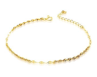 May include: A delicate gold-colored anklet with a variety of chain styles. The anklet features a combination of twisted rope, small flat oval, and delicate chain links. The adjustable chain allows for a comfortable fit. The anklet is a beautiful piece of jewelry.
