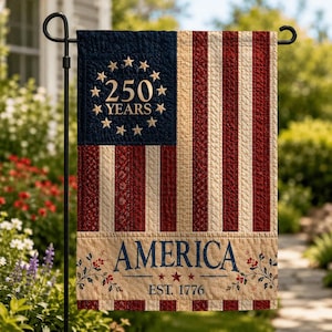 May include: A quilted garden flag featuring a dark blue canton with thirteen gold stars arranged in a circle around the text 250 YEARS. The flag has vertical red and cream stripes, with a bottom cream border displaying the text AMERICA EST. 1776.