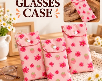 May include: Three rectangular fabric glasses cases in a light pink color featuring a repeating pattern of small red flowers and strawberries. Each case has a flap closure secured with a white snap button. The text GLASSES CASE is visible.