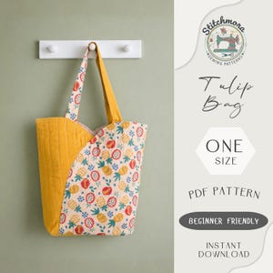 May include: A yellow quilted tote bag with a fruit pattern, hanging on a white wall hook. The bag has a curved design and a yellow handle. Text on the image reads "Tulip Bag", "One Size", and "Beginner Friendly".
