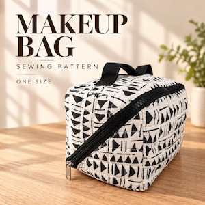 Può includere: Una trousse trapuntata con un motivo geometrico a triangoli bianchi e neri, dotata di chiusura a zip nera e manico superiore nero. Il testo MAKEUP BAG SEWING PATTERN ONE SIZE è stampato sullo sfondo sopra la borsa rettangolare.