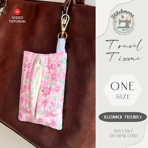 Peut inclure: Un étui à mouchoirs de voyage floral rose et vert, attaché à un sac en cuir marron avec un clip doré. Le support est matelassé et possède un intérieur blanc. Le texte sur l'image indique "Travel Tissue", "One Size" et "Beginner Friendly".