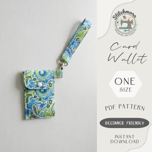 May include: A card wallet with a blue, green, and white paisley pattern, featuring a matching wrist strap. The wallet has a snap closure and a silver clasp. The image includes text: "Card Wallet", "One Size", "PDF Pattern", "Beginner Friendly", and "Instant Download".