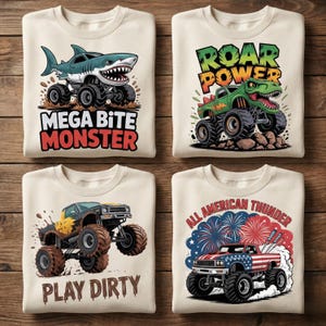 Może przedstawiać: Cztery złożone kremowe bluzy z nadrukami monster trucków. Jedna przedstawia ciężarówkę rekina z napisem "Mega Bite Monster". Inna ma ciężarówkę z dinozaurem z napisem "Roar Power". Trzecia ma ciężarówkę z napisem "Play Dirty". Ostatnia ma ciężarówkę z amerykańską flagą z napisem "All American Thunder".