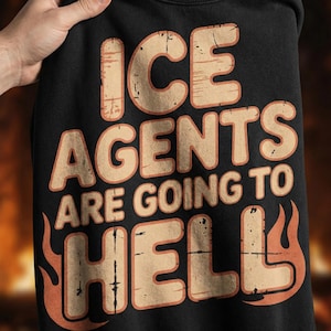May include: Black sweatshirt with the text "ICE AGENTS ARE GOING TO HELL" in a distressed, orange and tan font. The word "HELL" is stylized with flames. The sweatshirt is held up by a hand.