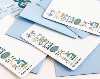 May include: Two white note cards with a blue background. The note cards feature a colorful illustration of science-related icons, including a DNA strand, a beaker, a microscope, and a neuron. The text "From the desk of Aaron Warren" is printed on the bottom of each card.
