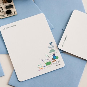 May include: Three blank white note cards with blue envelopes. The note cards have a handwritten name, "Ms. Grace Martin", and a small graphic of a mathematical equation with the number pi. The note cards are from La Petite Note.