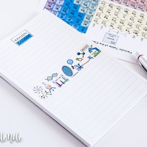 Peut inclure: Un bloc-notes blanc avec des illustrations scientifiques bleues et vertes qui épellent le mot "science". Le bloc-notes a un intérieur ligné et une bordure noire. Le nom "KAYLEEN" est écrit en haut du bloc-notes. Un stylo blanc avec une gomme rose est posé sur une surface blanche à côté du bloc-notes.