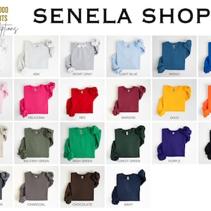 May include: A selection of Gildan 18000 sweatshirts in a range of colours: white, ash, sport grey, light blue, indigo, royal, light pink, heliconia, red, maroon, gold, orange, sand, military green, irish green, forest green, purple, black, dark heather, charcoal, chocolate, and navy. The text "SENELA SHOP" is displayed.