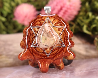 May include: A brown wooden pendant with a silver-colored geometric design and a clear resin inlay featuring a light brown and green stone.