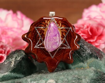 Puede incluir: Un colgante de piedra preciosa púrpura y blanca con un engaste de plata, engastado en un diseño de estrella de resina marrón.