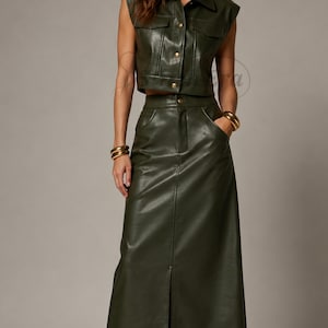 May include: A dark olive green two-piece set consisting of a sleeveless cropped waistcoat with a collar, front button closure, and two chest pockets, paired with a matching high-waisted maxi skirt featuring a front centre slit and side pockets.