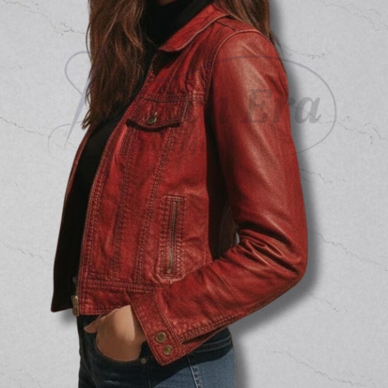 May include: A red leather jacket with a collared neckline, a small chest pocket, and a zippered front. The jacket has buttoned cuffs and a tailored fit. The model is wearing a black turtleneck underneath. The jacket is a deep shade of red.
