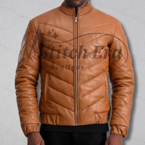 Puede incluir: Chaqueta de cuero marrón claro con diseño acolchado. La chaqueta tiene cuello alzado, cierre de cremallera y dos bolsillos delanteros. Las mangas son largas y tienen puños acanalados. La chaqueta es de talla mediana.