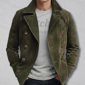May include: An olive green double-breasted jacket with four buttons. The jacket features a wide lapel and a classic design. The model is wearing a grey t-shirt. The jacket is made of a soft, suede-like material.