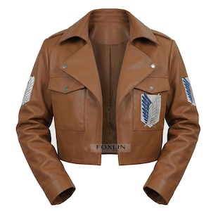 Könnte beinhalten: Braune Lederjacke mit kurzem Design. Die Jacke hat zwei Vordertaschen, einen Reverskragen und Aufnäher mit einem geflügelten Emblem auf jedem Ärmel. Die Jacke hat einen Knopfverschluss und wird auf weißem Hintergrund präsentiert.