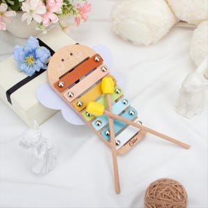 May include: Wooden xylophone toy with a smiling face design, colorful bars, and two yellow mallets. The xylophone has a light brown wooden frame, with a white cloud-shaped accent. The name "Chloe" is written on the xylophone.