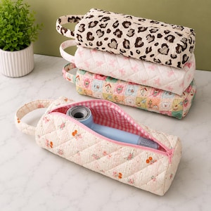 May include: Four quilted cylindrical storage cases with side handles and zipper closures. One case features a leopard print, one has a pink butterfly pattern, one displays a multi-colored bear and house motif, and one shows a cherry print with a pink gingham interior containing a light blue hair dryer.
