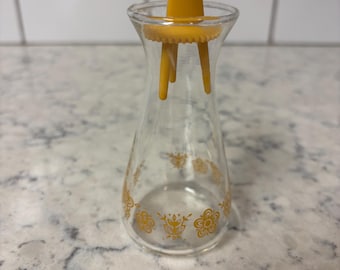 Vintage Pyrex 'Butterfly Gold' glass salt shaker with yellow plastic lid.