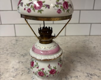 Vintage porcelain hurricane oil lamp with floral rose pattern and brass accents.