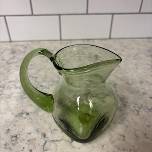 Peut inclure: Une tasse en céramique blanche avec une anse noire et le texte "But First, Coffee" dans un style manuscrit. La tasse est sur une surface blanche. Pour boissons chaudes.
