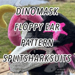 Może przedstawiać: Zbliżenie na Dinomask z wzorem klapniętego ucha. Maska jest czarna, biała i różowa, z widocznym tekstem "SPLITSHARKSUITS" i "DINOMASK FLOPPY EAR PATTERN". Projekt zawiera różowe akcenty i żółte ucho.