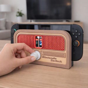 Può includere: Una base di ricarica per Nintendo Switch in plastica marrone e beige progettata come una radio vintage, con una griglia per altoparlanti rossa, una manopola bianca e la scritta Nintendo Switch in rilievo sul pannello frontale.