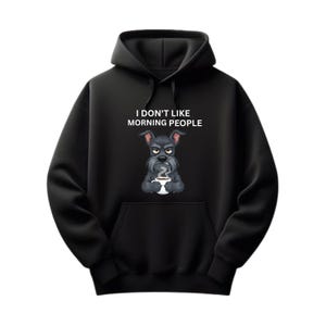 Könnte beinhalten: Schwarzer Kapuzenpullover mit einer Vordertasche und einer Kapuze mit Kordelzug. Die Grafik auf der Vorderseite zeigt einen mürrischen Cartoon-Hund, der eine Kaffeetasse hält, mit dem Text "I DON'T LIKE MORNING PEOPLE" über dem Hund.