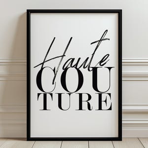 Peut inclure: Une affiche encadrée présentant le texte Haute Couture en une combinaison d'écriture manuscrite noire et de typographie serif grasse sur un fond blanc. Le cadre est fin et noir, entourant l'impression rectangulaire avec des lignes épurées.