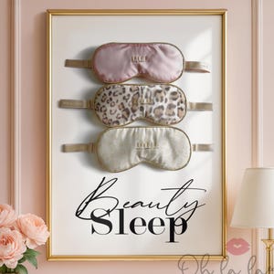 Puede incluir: Una impresión enmarcada con tres antifaces para dormir. La máscara superior es rosa, la del medio tiene un estampado de leopardo y la inferior es de color crema con un estampado floral. Las palabras "Beauty Sleep" están escritas en cursiva.