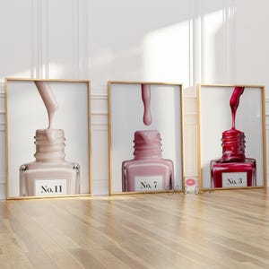 May include: Three framed wall art prints featuring nail polish bottles with dripping brushes. The left print shows a beige bottle labelled No. 11, the centre shows a light pink bottle labelled No. 7, and the right shows a deep red bottle labelled No. 3.