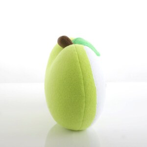 May include: A plush green apple pillow with a brown stem and a green leaf. The pillow is made of soft, fuzzy fabric and is perfect for cuddling.