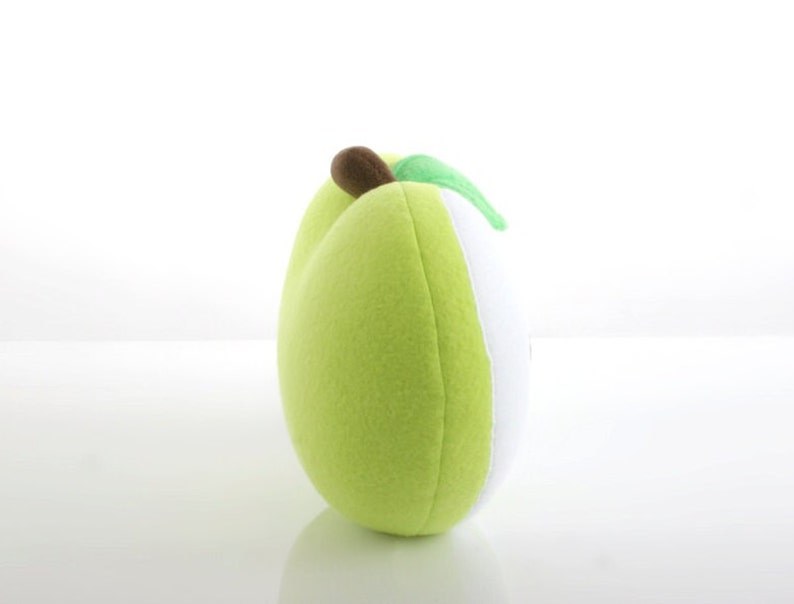 May include: A plush green apple pillow with a brown stem and a green leaf. The pillow is made of soft, fuzzy fabric and is perfect for cuddling.