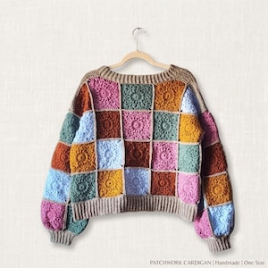 May include: A long-sleeve patchwork cardigan made of crocheted granny squares in various colors including pink, light blue, mustard yellow, dark brown, and sage green. The garment features a ribbed tan neckline, cuffs, and hem. Text reads: PATCHWORK CARDIGAN | Handmade | One Size.