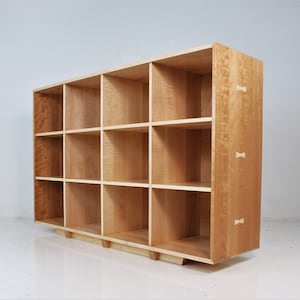 May include: A wooden bookcase with 12 open shelves. The bookcase is made of light wood with a natural finish. The shelves are evenly spaced and the bookcase has a simple, modern design.