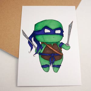 Op de afbeelding: Een cartoonillustratie van een groene Teenage Mutant Ninja Turtle met een blauw masker en een bruine riem die twee zilveren katanas vasthoudt. De schildpad draagt ​​een blauwe bandana en heeft een groene schild.
