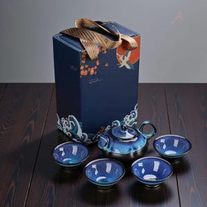 Può includere: Servizio da tè in ceramica blu con teiera e quattro tazze abbinate, presentato con un cofanetto regalo decorativo. Il set presenta una finitura lucida e strutturata e una base color argento. Il cofanetto regalo è blu navy con manico dorato.