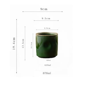 May include: A dark green ceramic cup with a glossy finish. The cup is cylindrical, 3.9 inches in diameter, and 7.6 inches tall. The image also shows the cup's capacity, which is 16.9, 20.6, and 29.7 fluid ounces.
