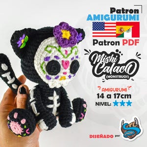 Puede incluir: Un amigurumi de gato tejido a ganchillo en negro con cara de calavera blanca, bordados florales coloridos, una flor morada en la cabeza y detalles de caja torácica esquelética. El texto incluye Patron Amigurumi, Mishi Calaco y 14 a 17cm.