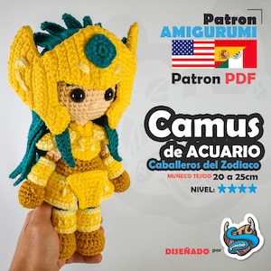 Può includere: Bambola all'uncinetto fatta a mano di un personaggio della serie Zodiac Knights. La bambola è principalmente gialla con accenti turchese, indossa un elmo e un'armatura. Il testo "Camus de Acuario" è visibile.