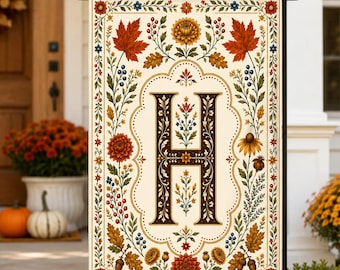 May include: A rectangular garden flag featuring a large, dark brown letter H centered within an ornate frame. The design includes autumn-themed illustrations of orange maple leaves, yellow chrysanthemums, red berries, and acorns on a cream background.