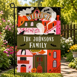 May include: A rectangular garden flag featuring a colorful Halloween illustration of houses, ghosts, bats, and a pumpkin. The text WELCOME is at the top, and the text THE JOHNSONS FAMILY is centered on a dark green horizontal banner.