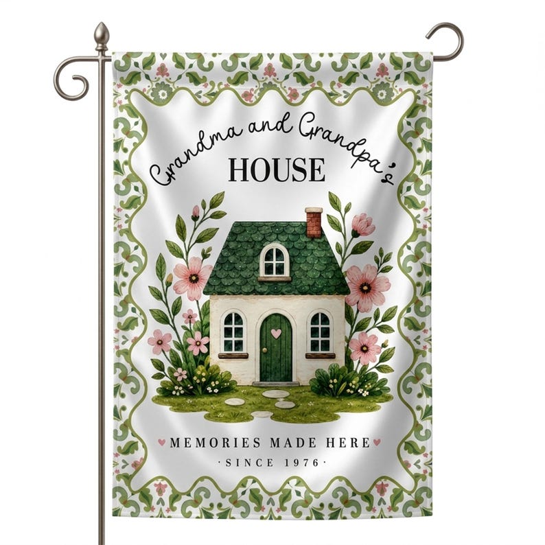 May include: A decorative garden flag featuring a watercolor illustration of a house with a green roof and door, surrounded by pink flowers and greenery. The flag reads "Grandma and Grandpa's HOUSE" and "MEMORIES MADE HERE - SINCE 1976."
