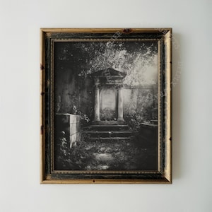 May include: A framed black and white photograph depicting a stone mausoleum with columns and steps, surrounded by overgrown foliage and trees. The image is enclosed in a dark, distressed wooden frame with a gold-toned inner border detail.