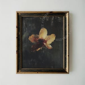 Puede incluir: Impresión artística floral enmarcada. La obra presenta un primer plano de una flor amarilla y marrón con un centro oscuro, sobre un fondo oscuro. El marco es dorado y negro.