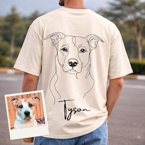 Könnte beinhalten: Cremefarbenes T-Shirt mit einer minimalistischen schwarzen Strichzeichnung eines Hundegesichts auf dem Rücken. Der Name des Hundes, "Tyson", ist in Kursivschrift unter der Zeichnung geschrieben. Ein kleines Foto des Hundes befindet sich in der unteren linken Ecke.