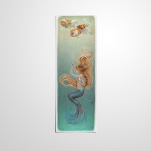 May include: A mermaid with long, flowing red hair holds onto strings attached to three goldfish. The goldfish are floating in the air like balloons. The mermaid is wearing a teal and purple tail and is swimming in a turquoise blue water.